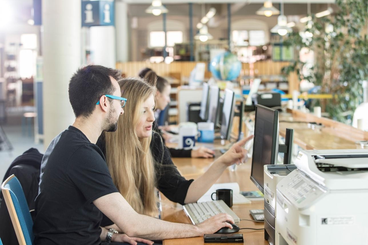 Woman explains something to man on computer