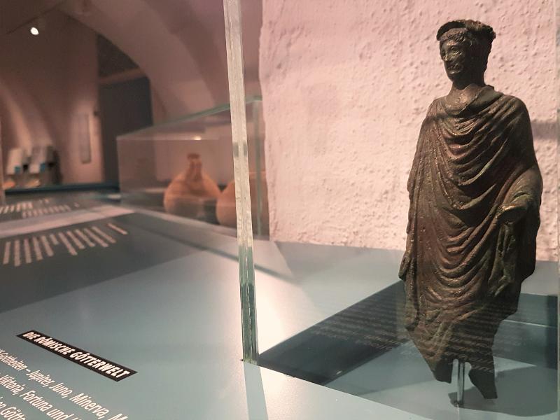 naher Blick in die Ausstellungsvitrine "Römische Götterwelt", zu sehen ist eine Skulptur