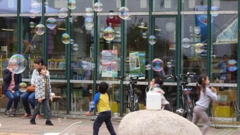 Kinder mit Seifenblasen vor Bibliothek - Link zur Seite Engagement für Geflüchtete