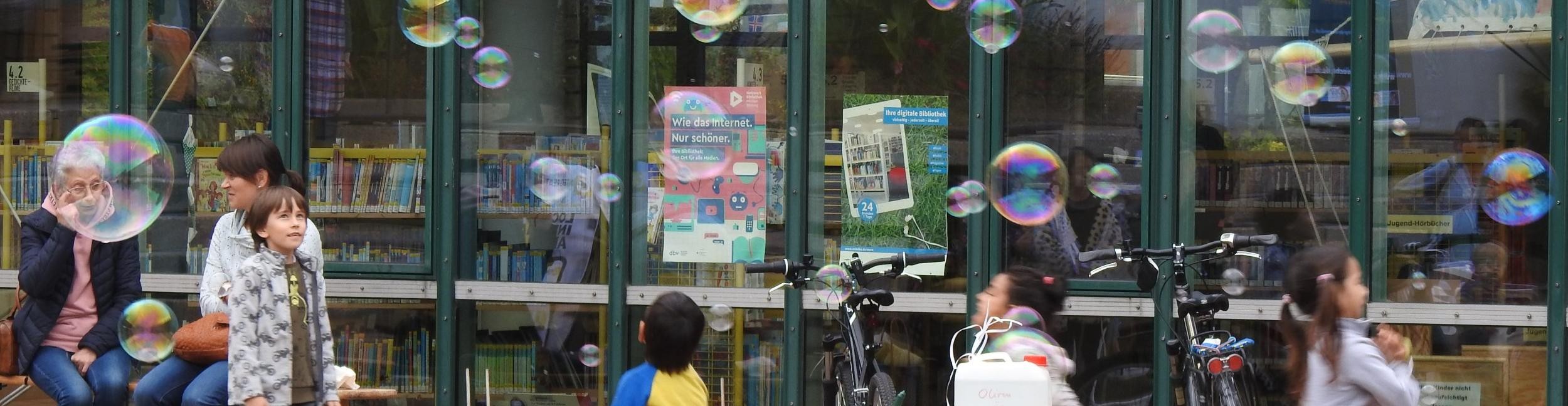 Kinder mit Seifenblasen vor Bibliothek
