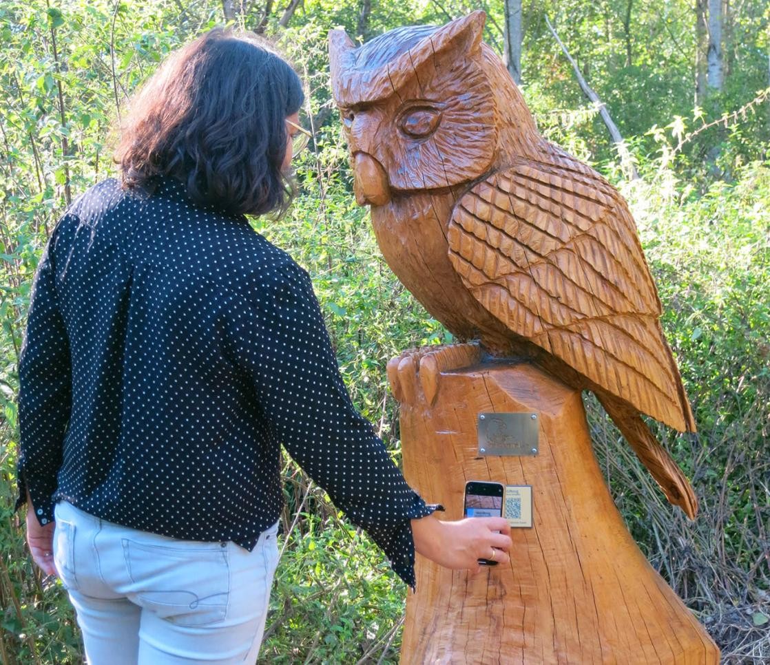 Frau scannt QR-Code an der Station Eule bei der Rheinauen-Runde ab