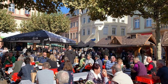 Menschen sitzen auf Bänken auf dem Marktplatz beim Verkaufsoffenen Sonntag in Rastatt