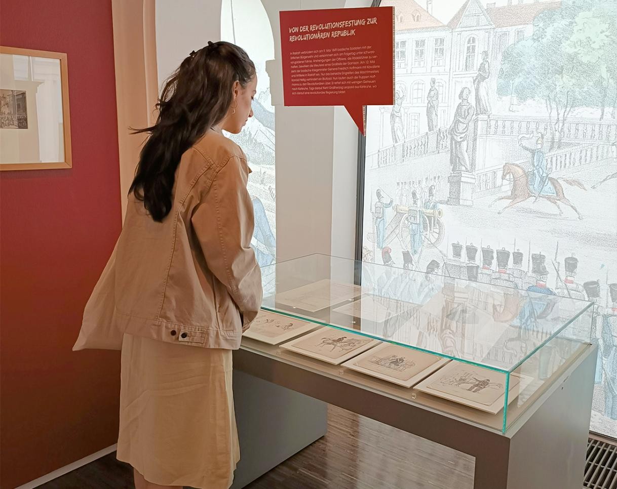 Woman standing in front of a display case in the town museum at the special exhibition: "For Freedom! Rastatt and the 1848/49 Revolution"