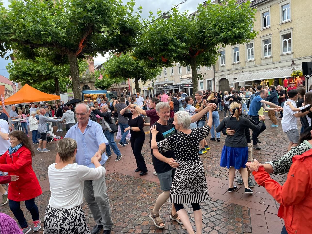 Menschen tanzen auf dem Marktplatz bei Tanz unter den Platanen