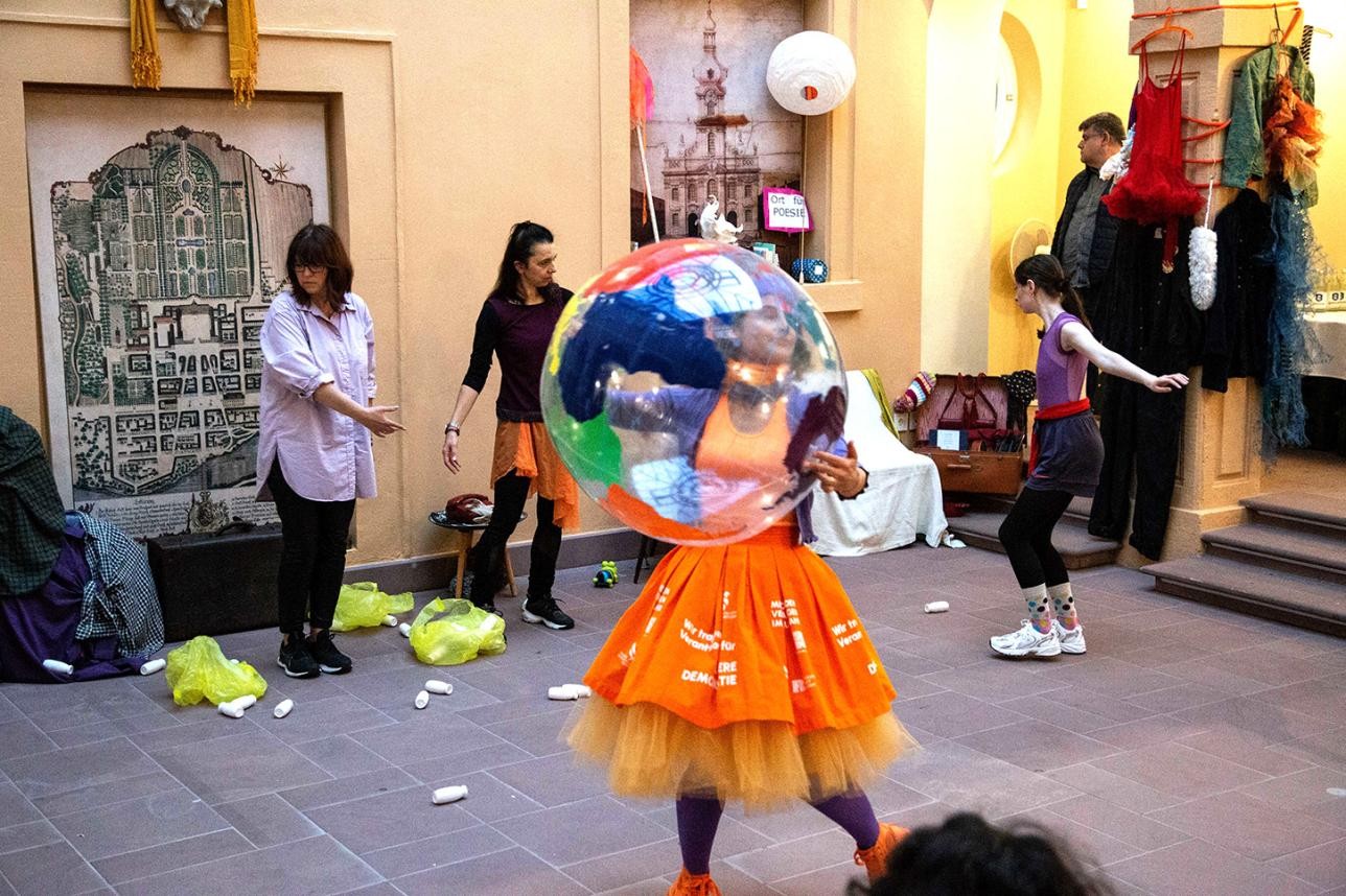 Femme dansant avec un gros ballon en plastique sur lequel est représentée la terre