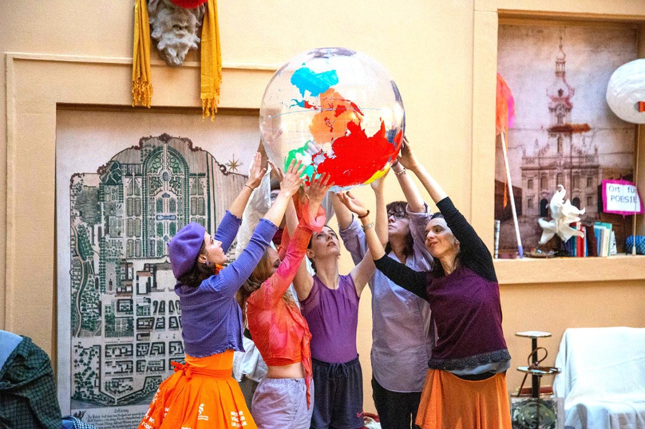 Un groupe de danseurs tient un gros ballon en plastique sur lequel est représentée la Terre