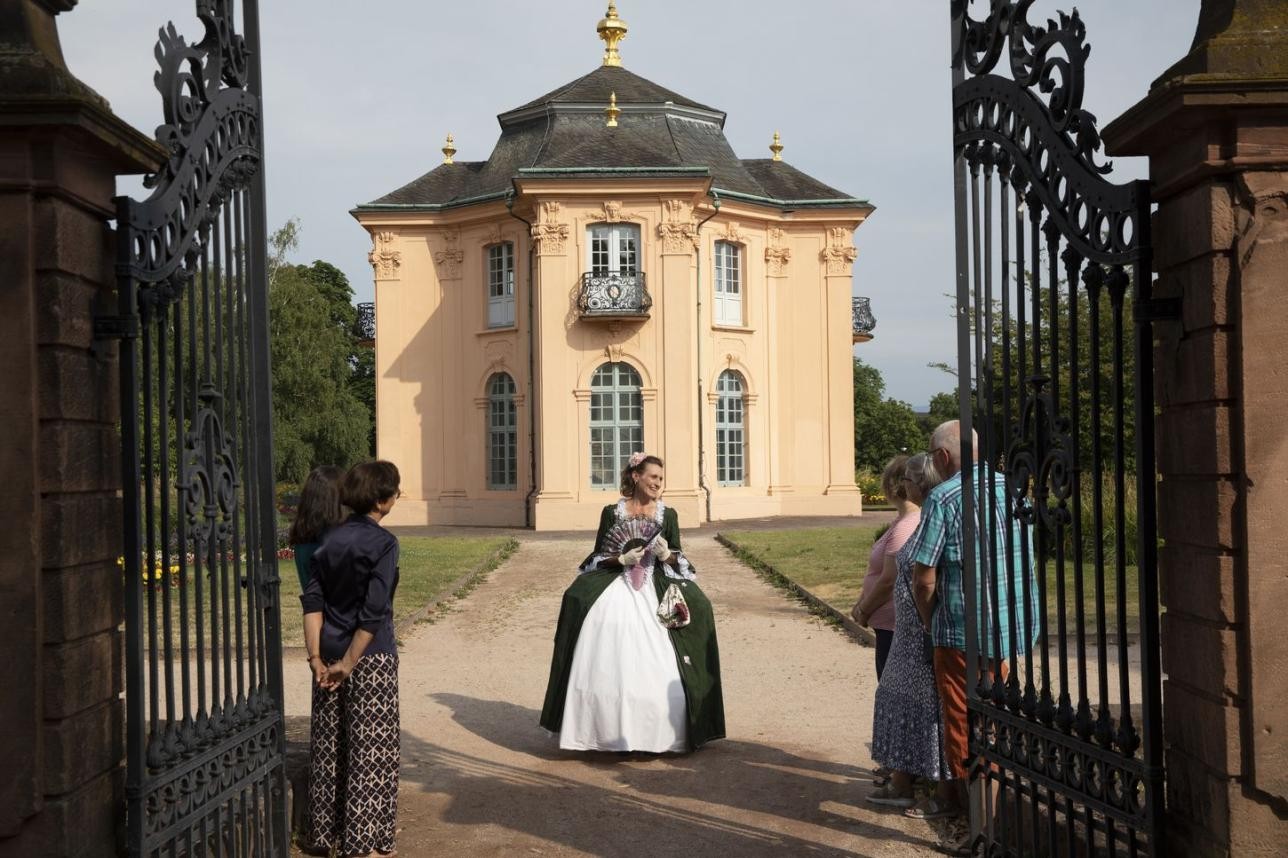 Die Führung durch Rastatt mit der Hofdame zählt zu den beliebtesten Gruppenführungen der Tourist-Information. Foto: Ulrike Klumpp Frau im historischen Kostüm vor Pagodenburg