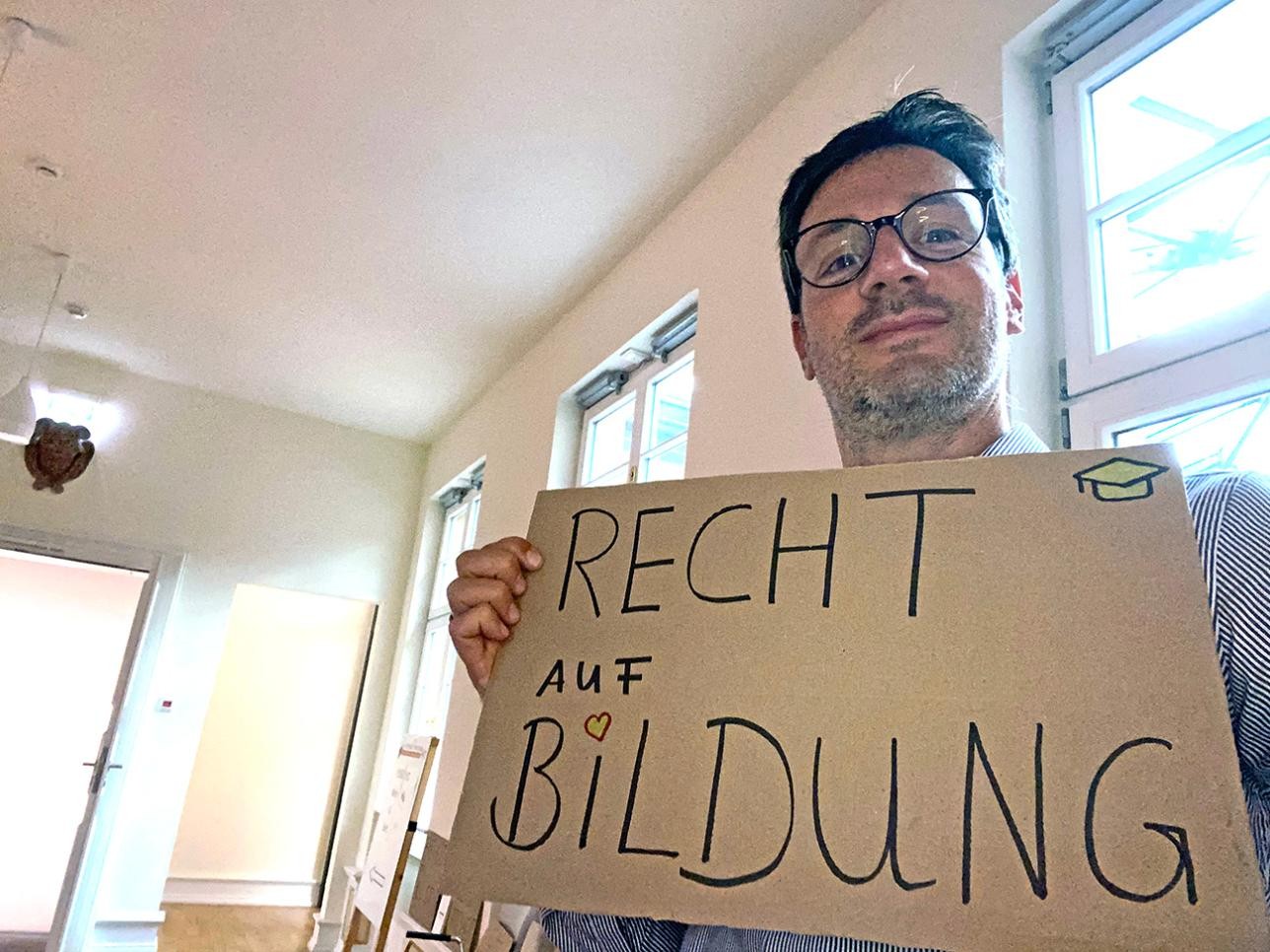 Mann macht ein Selfie mit einem Schild in der Hand