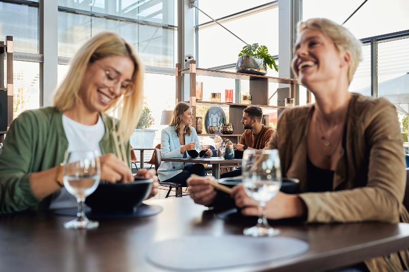 Zwei Frauen sitzen mit einem Getränk an einem Tisch