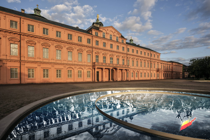 das Rastatter Schloss, im Vordergrund ein Spiegel, in welchem sich eine historische Szene mit Aufständischen spiegelt
