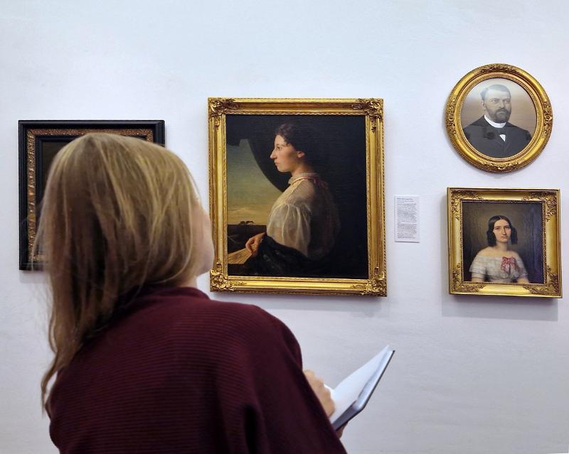 Person mit Skizzenbuch vor Gemälden in der Ausstellung