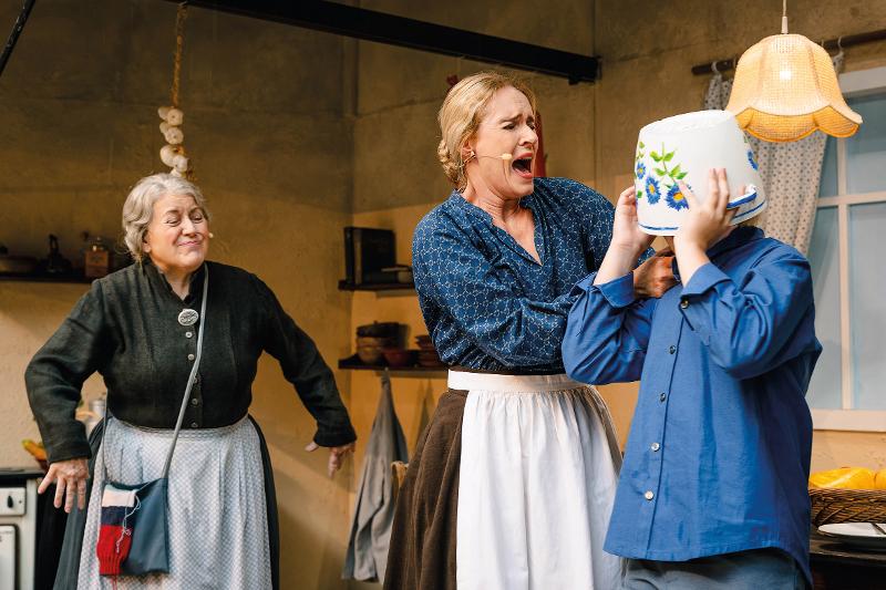 Zwei Frauen, ein Junge mit Schüssel auf dem Kopf.