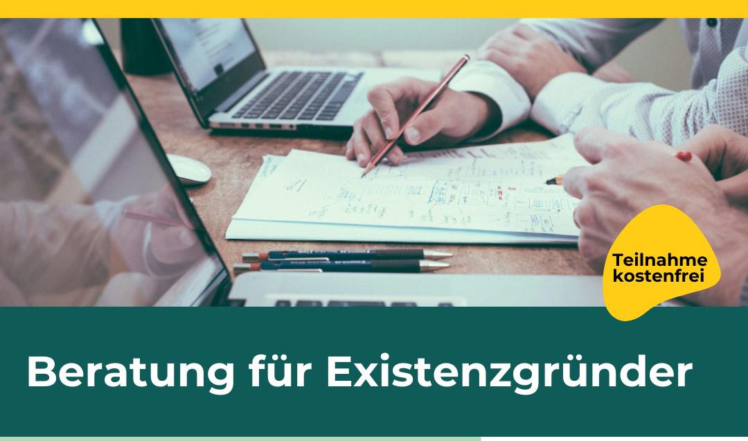 Laptops stehen auf einem Tisch. Ein Mann schrei9bt etwas auf ein Blatt Papier