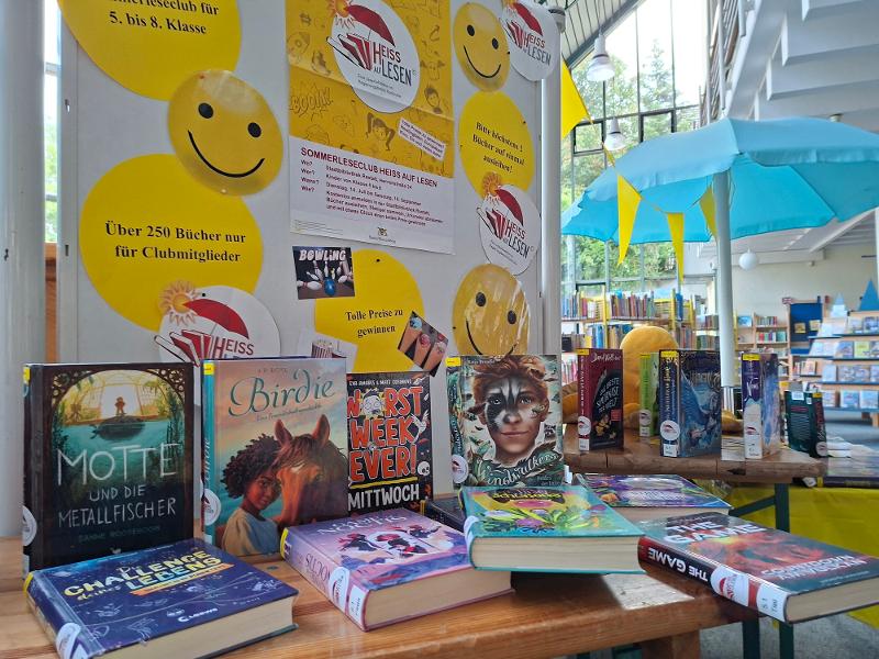 Ein Logo mit Büchern und Sonnenschirm wirbt für den Sommerleseclub der Stadtbibliothek