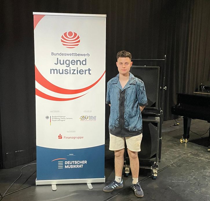 Nico Busch neben Banner Jugend musiziert