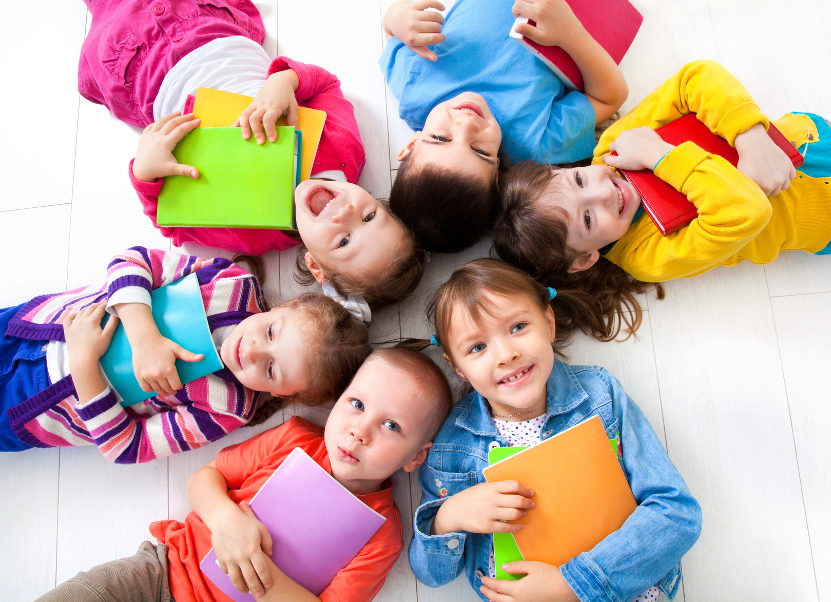 Kinder im Kreis liegend und in die Kamera lächelnd