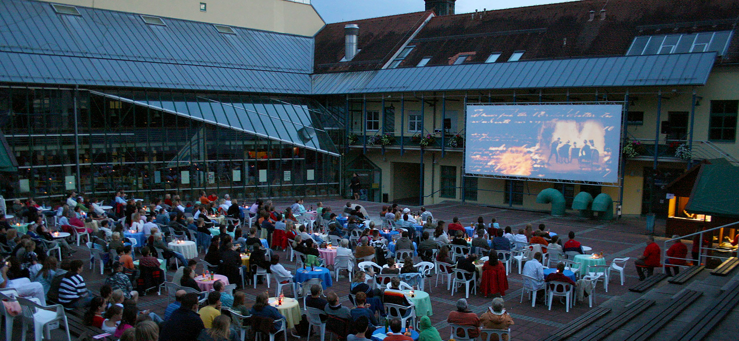 Menschen sitzen im Kulturforum und schauen einen Film